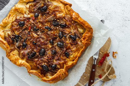 Home baked onion pie with anchovy and black olives served on parchment paper photo