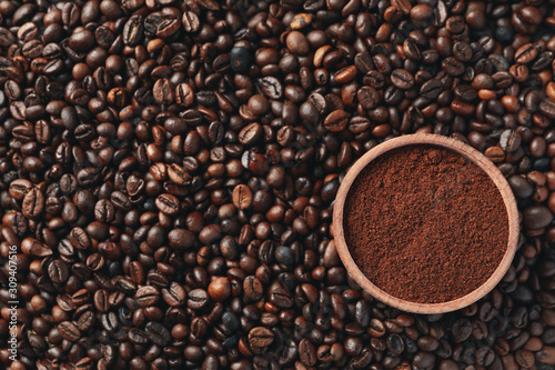 Textured background of coffee beans with bowl of powder, close up