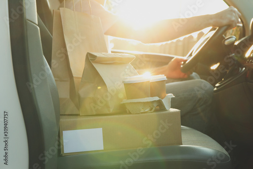 Φωτογραφία Blank box, coffee cups, paper packages and courier in car