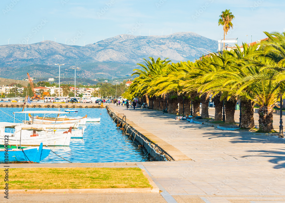 Nafplio sea promenade with palm trees and fishing boats in the water in Greece