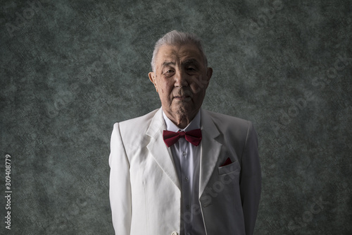 dark portrait of an old man in a white suit on a studio background