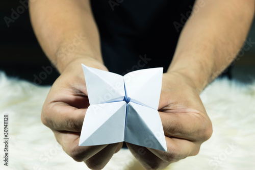The man's hand is holding a paper that predicts the fate known as Paper Fortune Tellers. To predict the future, work, love, fate, sometimes used as a fun game to play. There is space for copy space. photo