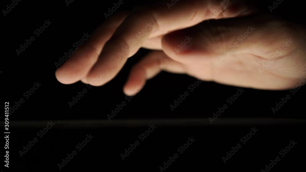 macro shot of digital gadget user using touch screen tablet in the dark