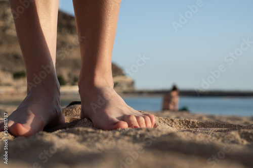 Closeup of a woman's legs and feet with nail polish on the sand in a beach. Summer holidays in Puerto Rico, Gran Canaria, Spain, beach resort and vacations concept