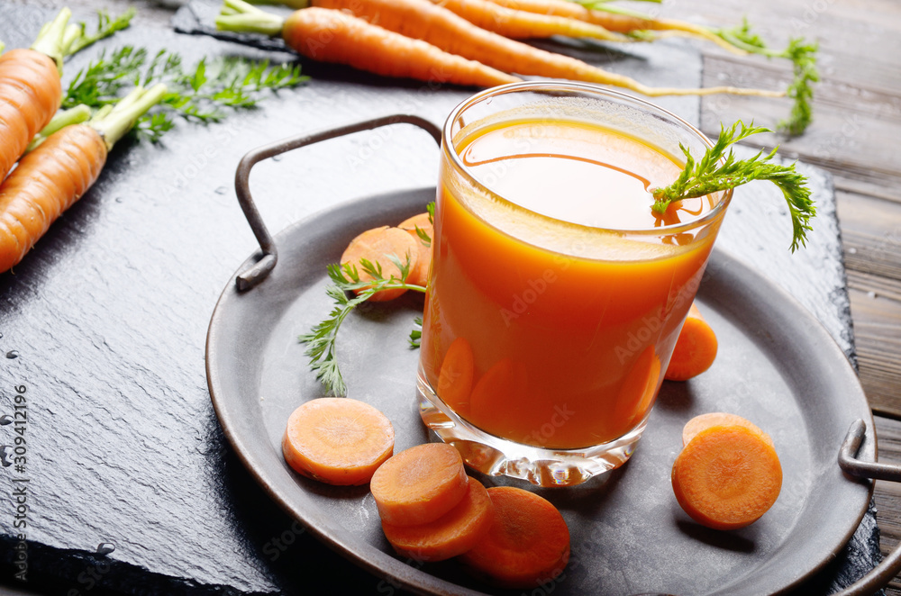 Vegetarian background of old tray with carrots and juice on slate stone Vegetarian background of old tray with carrots and juice on slate stone