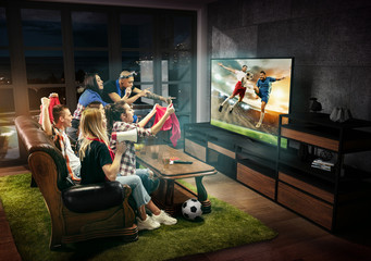 Group of friends watching TV, football match, sport together. Emotional men and women cheering for favourite team, look on goal and fighting for ball. Concept of friendship, leisure activity, emotions