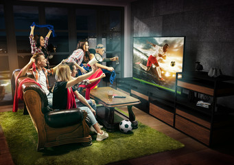 Group of friends watching TV, football match, sport together. Emotional men and women cheering for favourite team, look on goal and fighting for ball. Concept of friendship, leisure activity, emotions
