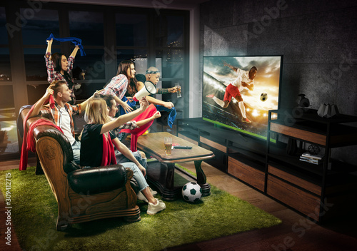 Group of friends watching TV, football match, sport together. Emotional men and women cheering for favourite team, look on goal and fighting for ball. Concept of friendship, leisure activity, emotions