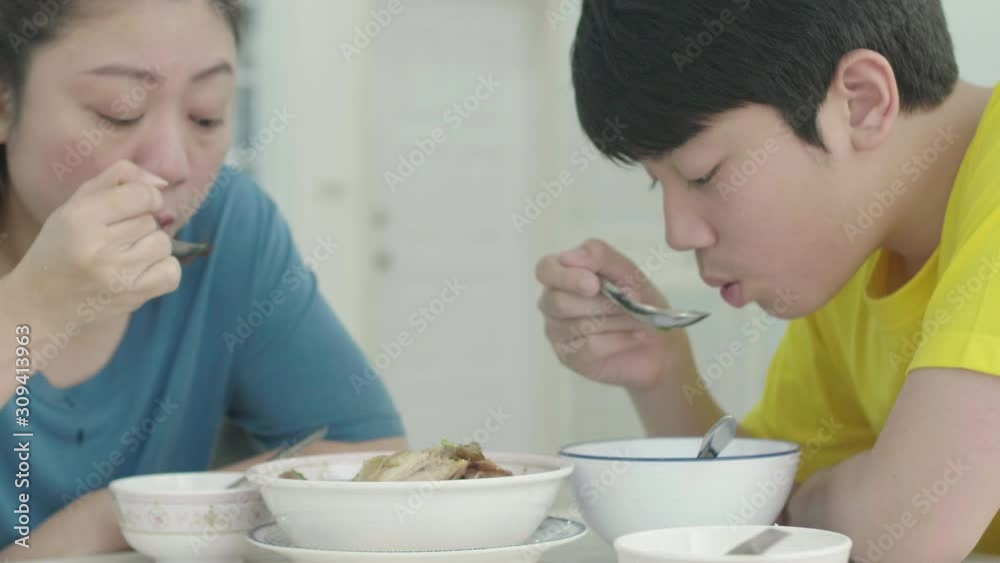Asian family mother with son having lunch at home and eating homemade chicken soup. Asian family mother with son having lunch at home and eating homemade chicken soup.