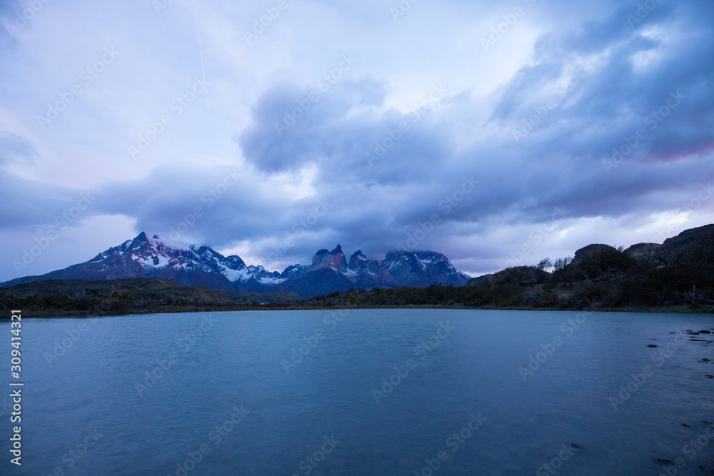 Cloudy sunrise over the Torres del Paine mountains that overlook the waters of a lake, Torres del Paine National Park, Chile