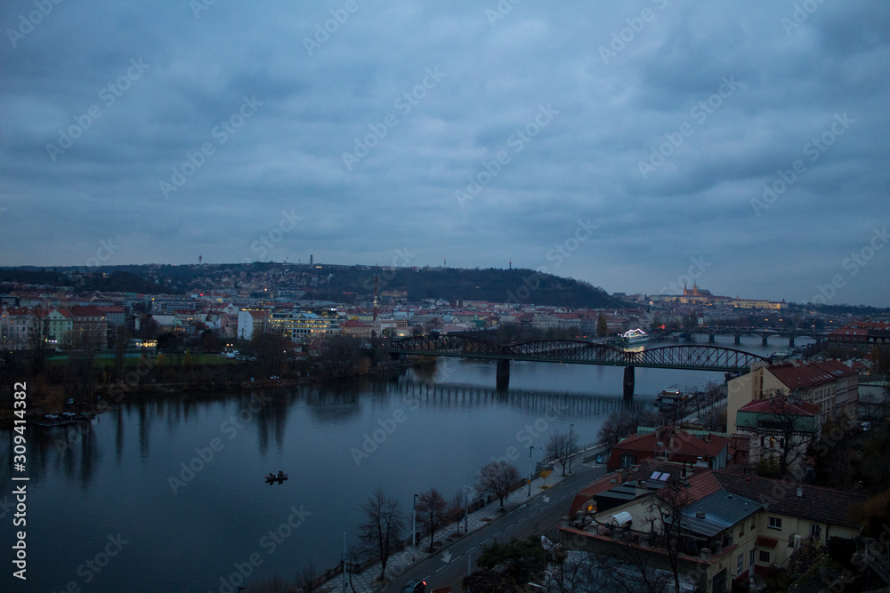  Winter panorama from Vysehrad Castle to the evening city of Prague, residential areas, the Vltava River, moorings with boats and boats and city transport.