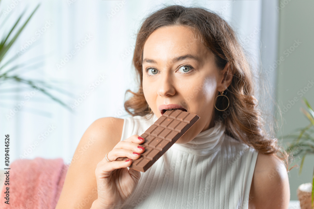 Young woman enjoying a chocolate bar at home. Young woman enjoying a chocolate bar at home.