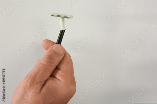 Man hand holds used disposable shaving stick. Mock-up on light background with shadow and copy space. Middle aged man face care concept closeup image