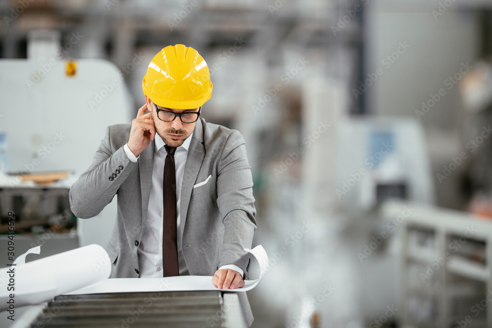 Businessman in warehouse. Young architect with helmet in suit. 
