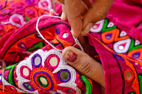 female needlework on fabric material close up view,Unidentified Tribal women sewing ethnic dresses,ahir embroidery art work close up view,Gujarat india embroidery