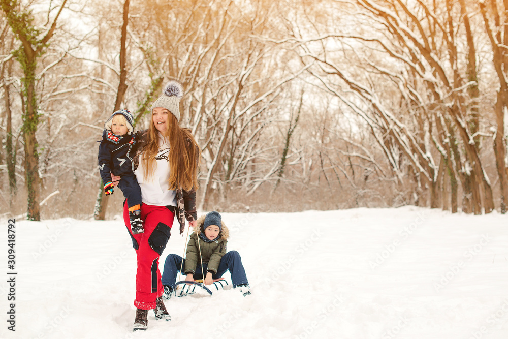 Happy mother and kids having fun with sledge in winter park. Family concept. Winter holidays Happy mother and kids having fun with sledge in winter park. Family concept. Winter holidays