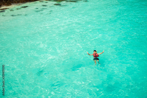 Young man snorkeling in clean water over coral reef.