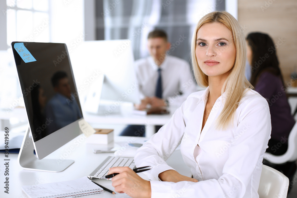 Business woman using computer at workplace in modern office. Secretary or female lawyer smiling and looks happy. Working for pleasure and success Business woman using computer at workplace in modern office. Secretary or female lawyer smiling and looks happy. Working for pleasure and success
