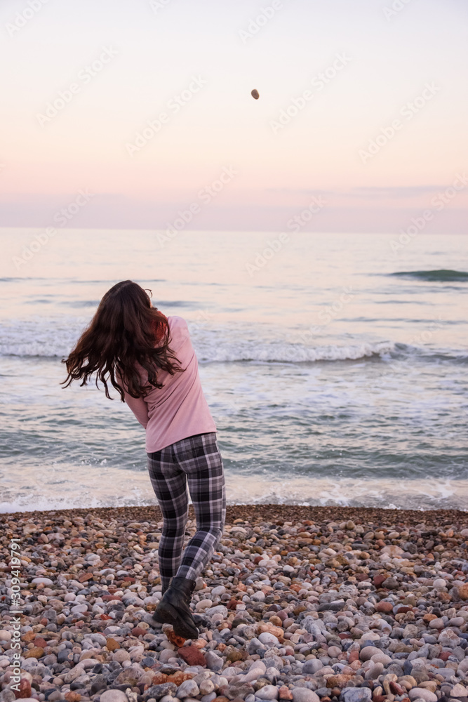 girl playing throw stones at the sea