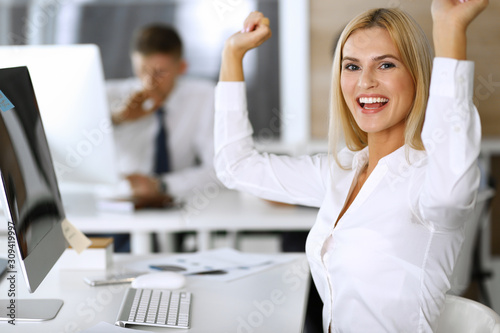 Business woman looks happy and excited at workplace in modern office. Secretary or female lawyer working for pleasure and success