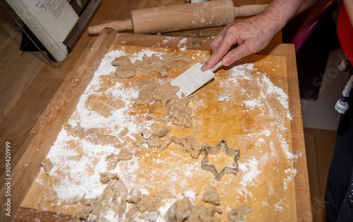 A woman gets a star-shaped christmas cookie off a board