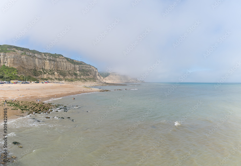 View of East Hill, cliffs and the Beach of Hastings, England, with seamist and sunshine, taken from the pier