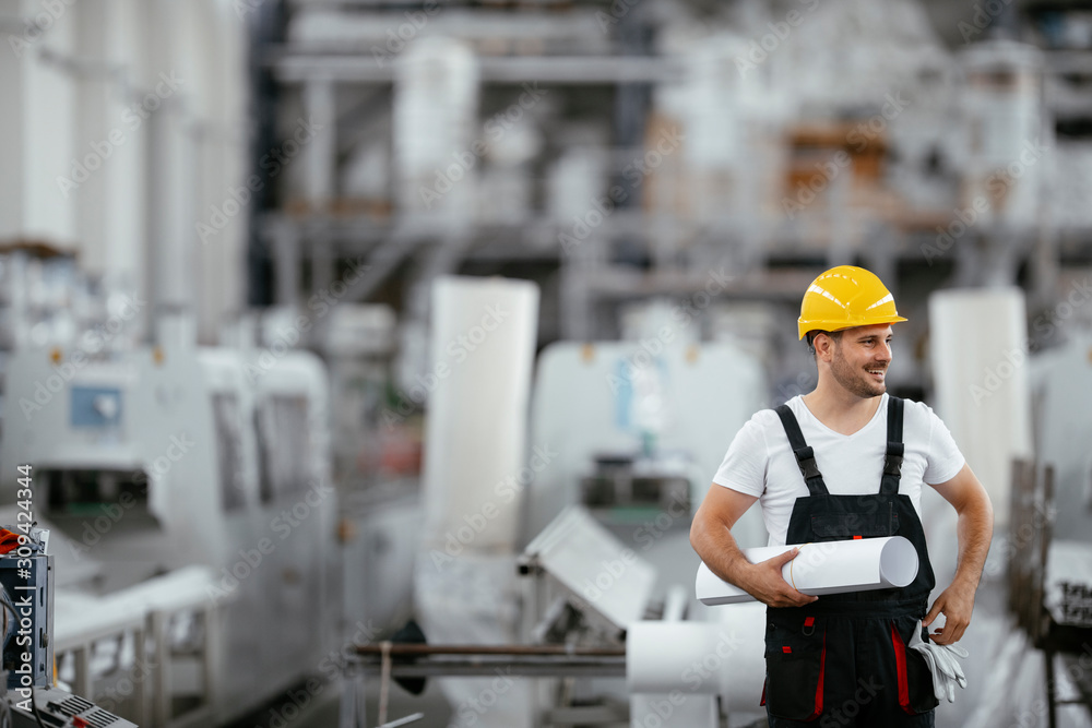Attractive worker in uniform. Man in factory with blueprint. Attractive worker in uniform. Man in factory with blueprint.