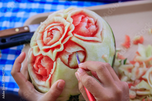 Woman is carving watermelon with a knife. photo