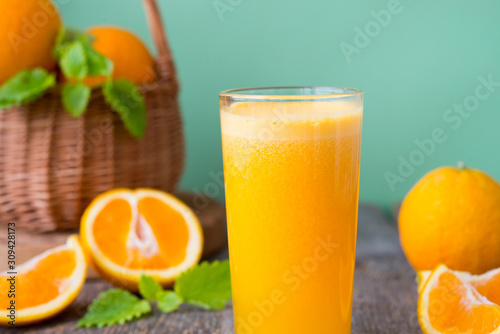 A glass of freshly squeezed juice surrounded by fresh oranges and tangerines. Horizontal photo.