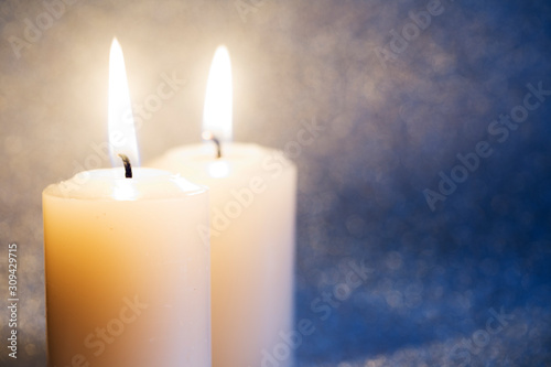 Zwei Kerzen vor silbernem Glitzerhintergrund