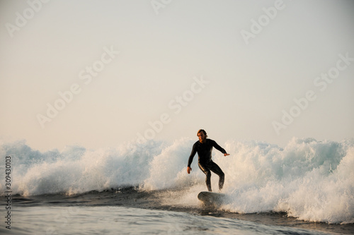 Canvas Print Surfer in black swimsuit rides the wave