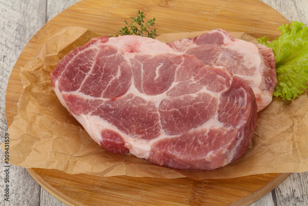 Raw pork steak over wooden board