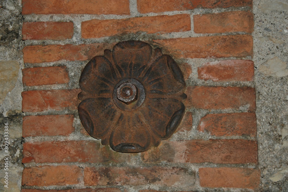 Rosone antico di ferro su un muro di mattoni