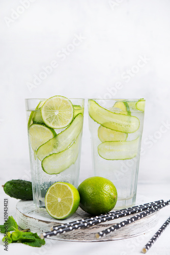 Homemade cold lemonade with lemon, lime, cucumber and mint on a white background.