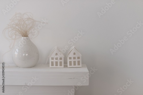 Minimalistic Christmas decor white cardboard houses and a vase with a feather grass.