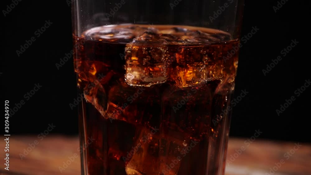 Tasty cola with ice on black background, closeup. Slow motion effect Tasty cola with ice on black background, closeup. Slow motion effect
