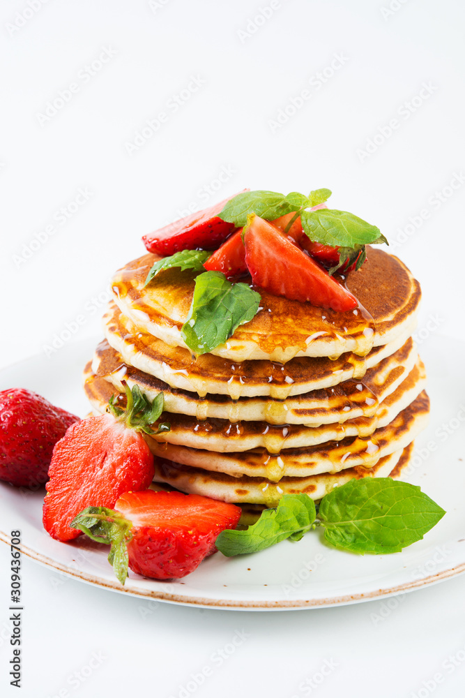 American pancakes lined with strawberries and honey poured on a white background. Classic American Breakfast. American pancakes lined with strawberries and honey poured on a white background. Classic American Breakfast.