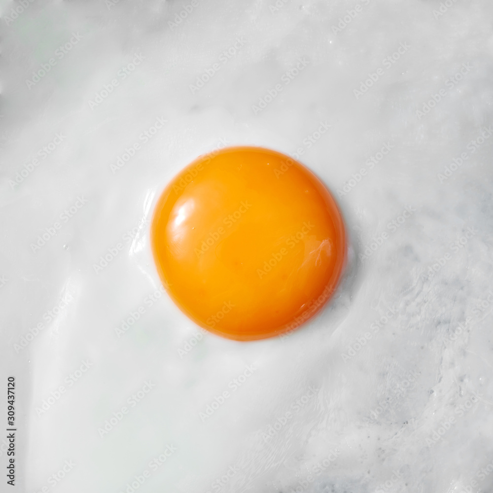 Fried egg with yellow yolk as a background, top view food cooking concept. Macro view. Fried egg with yellow yolk as a background, top view food cooking concept. Macro view.