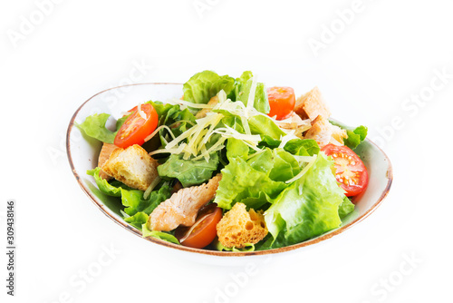 Caesar salad with chicken breast, tomatoes and wheat croutons in a plate on a white background. Horizontal photo.