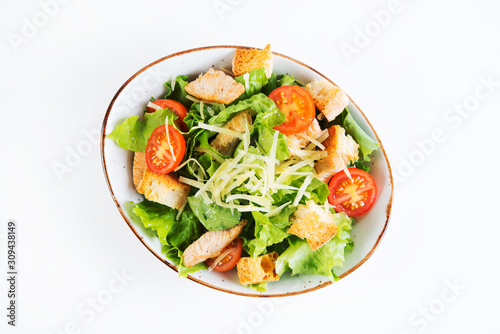 Caesar salad with chicken breast, tomatoes and wheat croutons in a plate on a white background. Horizontal photo. Top view