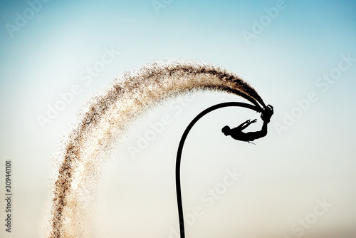 Silhouette image of a man showing the fly board (Aqua board) at sea ; The new spectacular sport