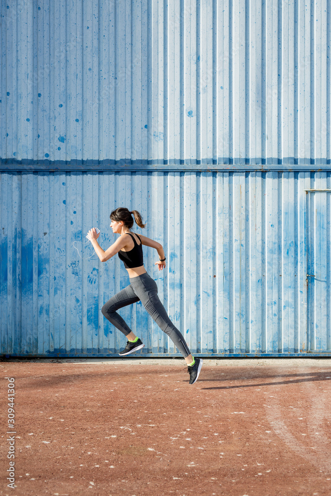Young runner passing in front of a big blue metal door Young runner passing in front of a big blue metal door