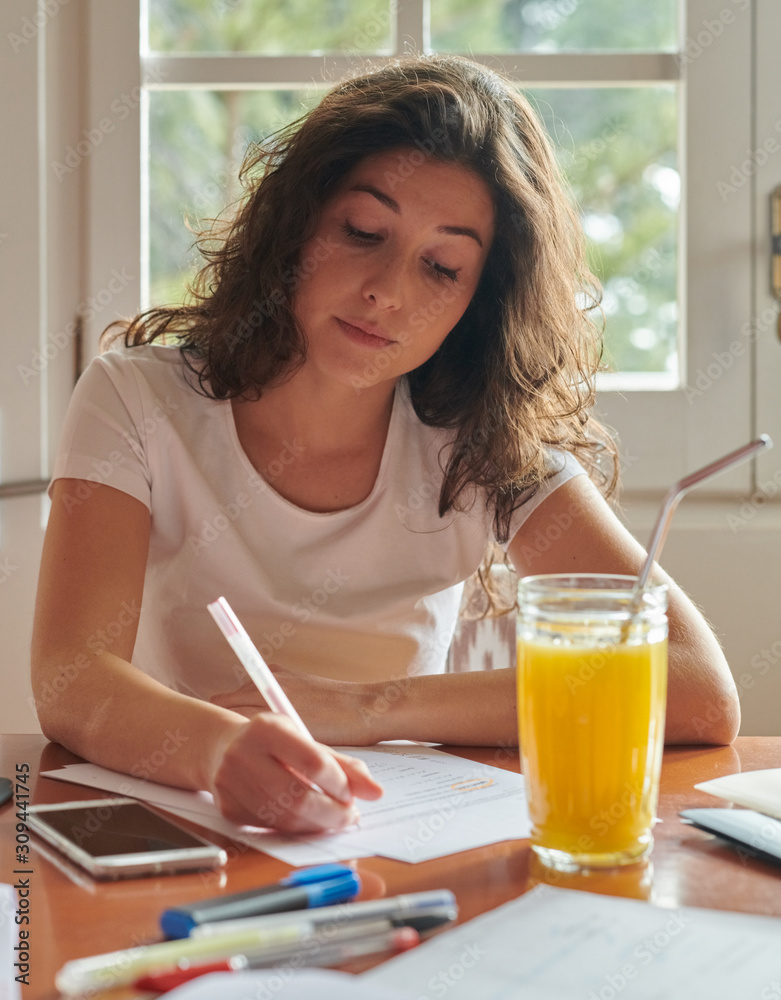 Woman writing on paper sitting at table Woman writing on paper sitting at table