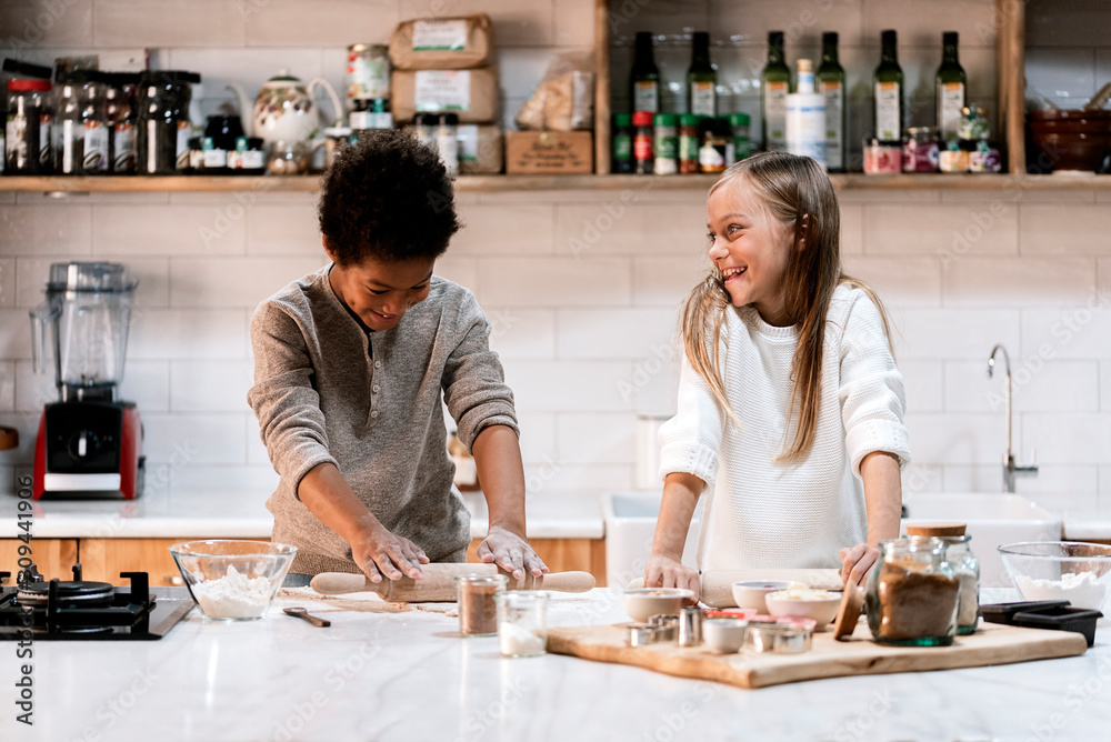 Happy children with rolling pins and dough in kitchen Happy children with rolling pins and dough in kitchen