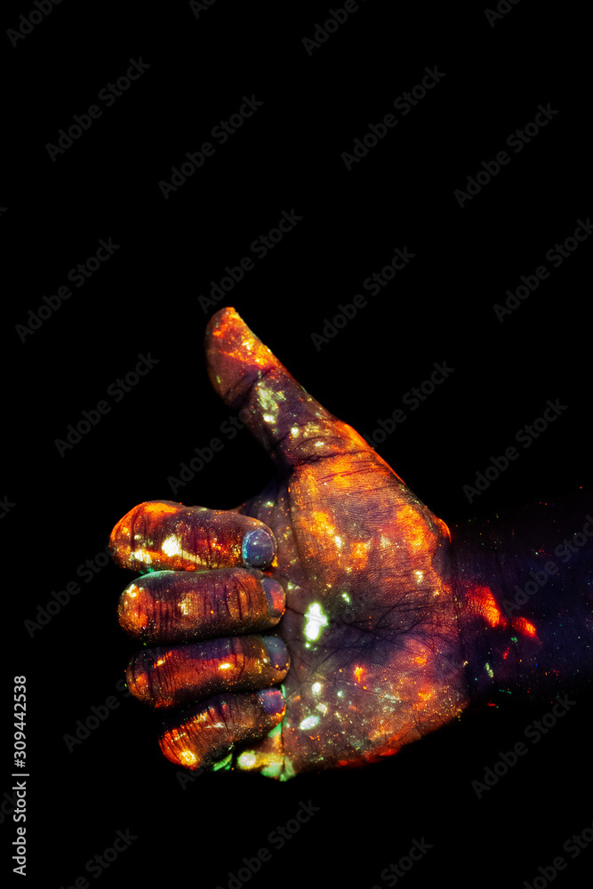 Male hand painted with fluorescent paint glowing in the darkness Male hand painted with fluorescent paint glowing in the darkness