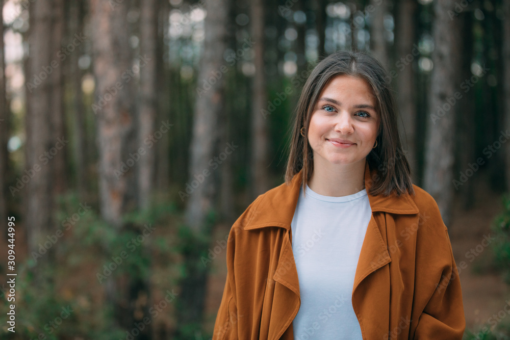 Portrait of a young woman in the forest. Smiling girl in nature among green trees. Portrait of a young woman in the forest. Smiling girl in nature among green trees.
