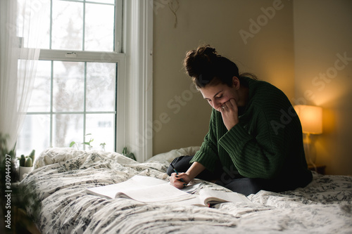 teen studying on her bed
