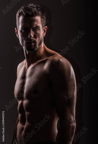 Obraz na płótnie Strong athletic man on black background, Fitness shaped muscle man posing w salonie