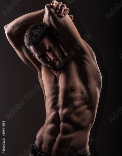 Strong athletic man on black background, Fitness shaped muscle man posing  © John Ilich
