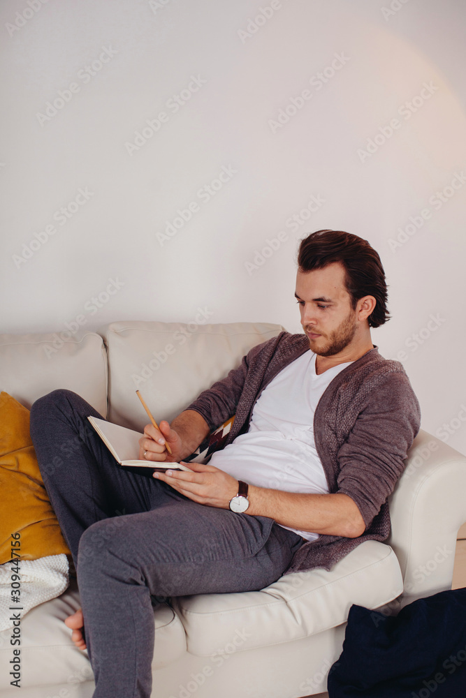 Young man writing in notebook indoors Young man writing in notebook indoors